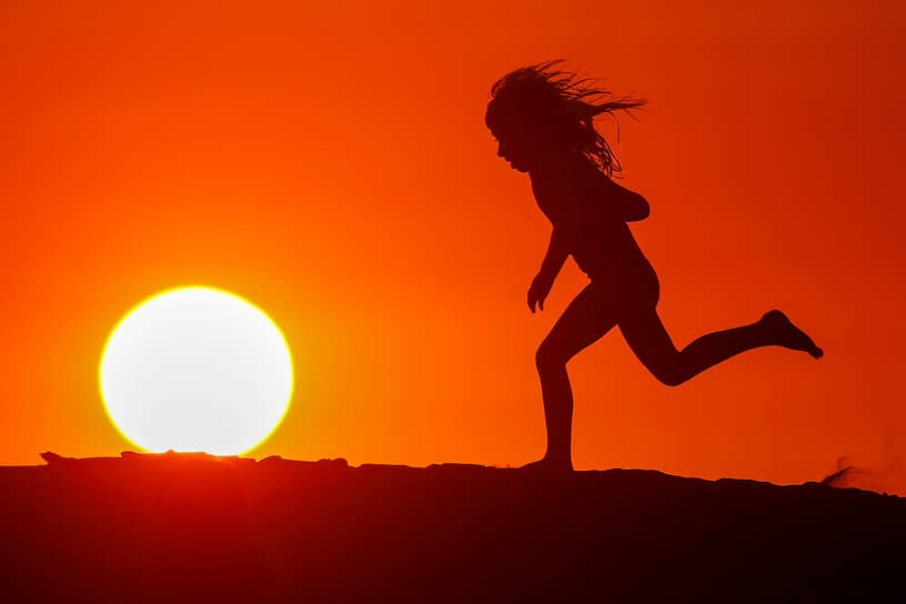 Карлсбад, штат Калифорния, США. Ребенок бежит по пляжу на рассвете 