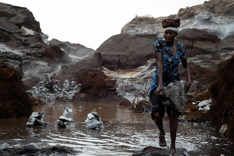 Уагадугу, Буркина-Фасо. Женщина выносит камни из лужи в гранитном карьере Писси в начале сезона дождей