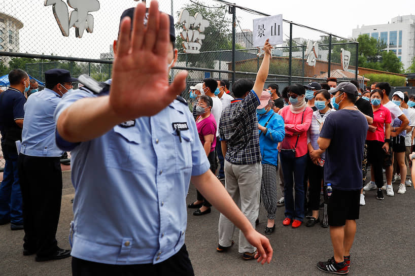 Пекин, Китай. Полицейский запрещает снимать людей, выстроившихся в очередь, чтобы сдать тест на коронавирус