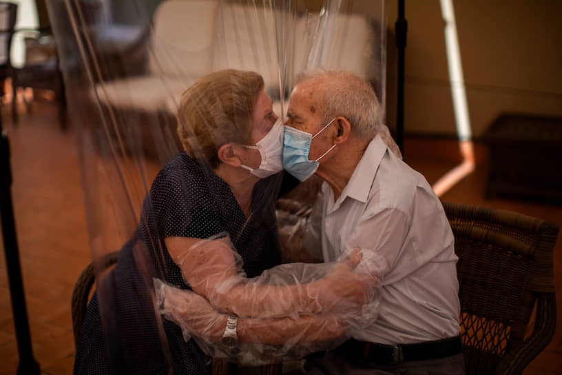 Барселона, Испания. Люди целуются через защитную пленку в доме престарелых 