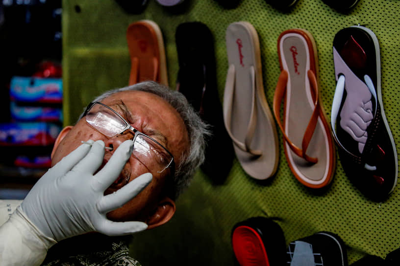 Джакарта, Индонезия. Медработник берет мазок на коронавирус у местного продавца