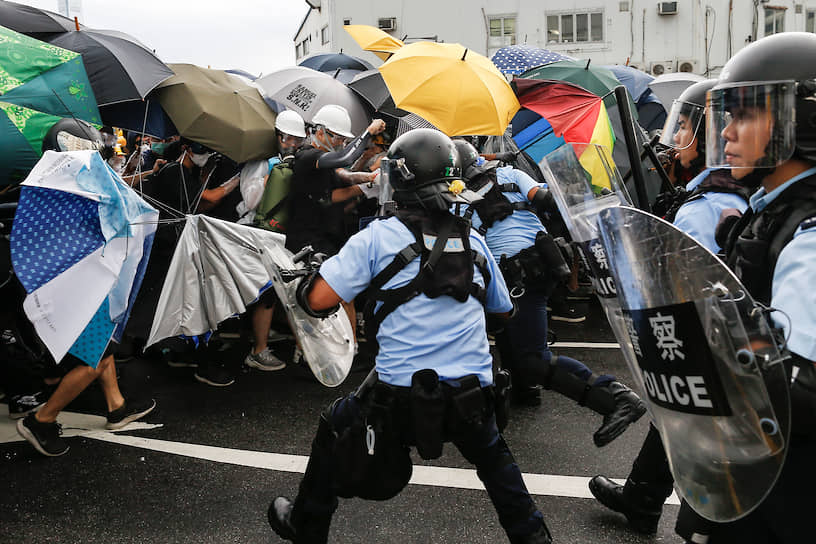 Полиция пытается разогнать протестующих возле места церемонии поднятия флага КНР, 2019 год