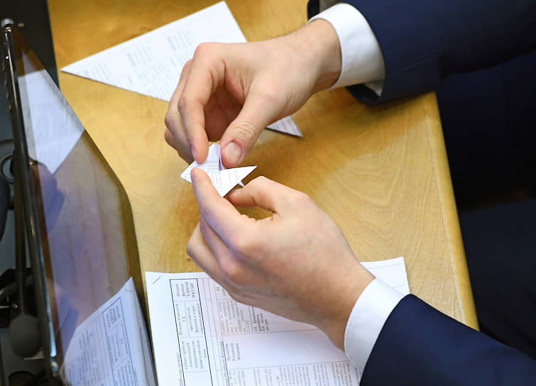 Депутат делает из бумаги оригами во время заседания