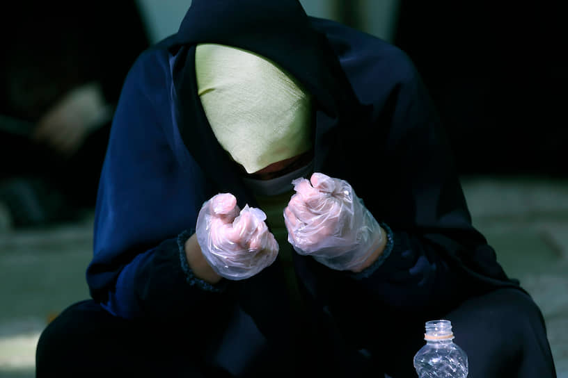 Тегеран, Иран. Женщина в защитной маске и перчатках во время молитвы 
