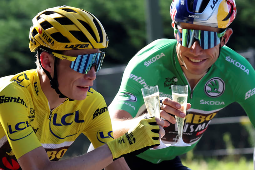 Датский спортсмен Йонас Вингегор (слева) пьет шампанское  на Елисейских полях в Париже после победы в общем зачете многодневной велогонки Тур де Франс с бельгийцем Вутом Ван Артом, 2022 год
