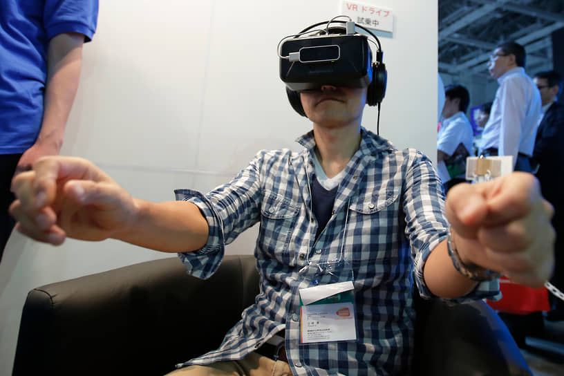 Посетитель международной выставки передовых технологий в Токио тестирует VR-симуляцию поездки по оживленным улицам города