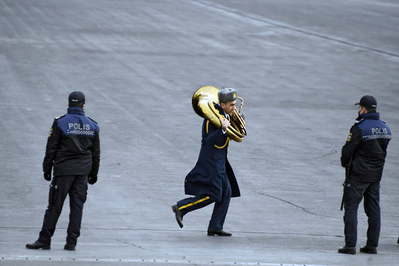 Музыкант военного оркестра и сотрудники полиции перед началом парада