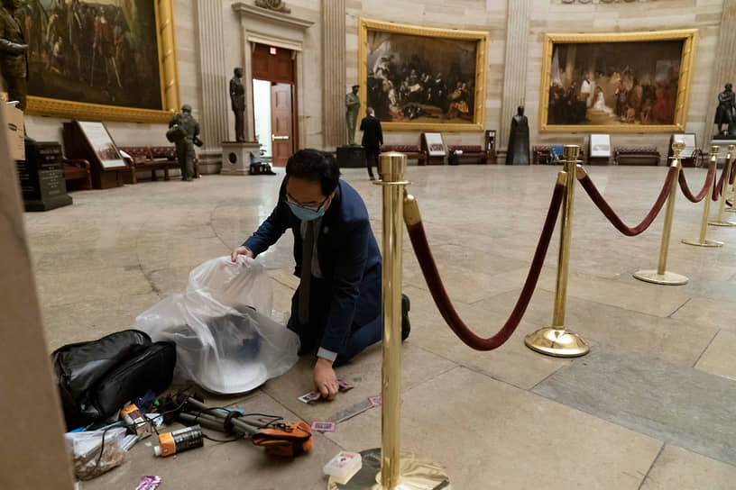 Член палаты представителей Энди Ким, штат Нью-Джерси, убирает мусор и личные вещи, разбросанные по полу Ротонды