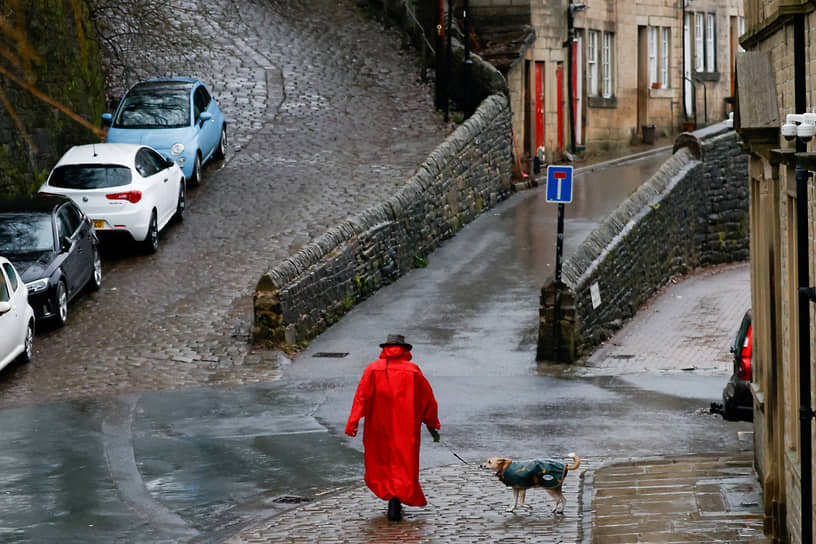 Хебден Бридж, Великобритания. Женщина выгуливает собаку в ожидании наводнения из-за надвигающегося шторма 