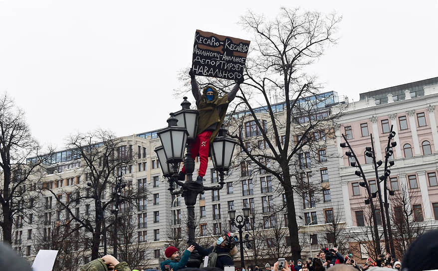 Мужчина с плакатом против Алексея Навального на фонарном столбе 