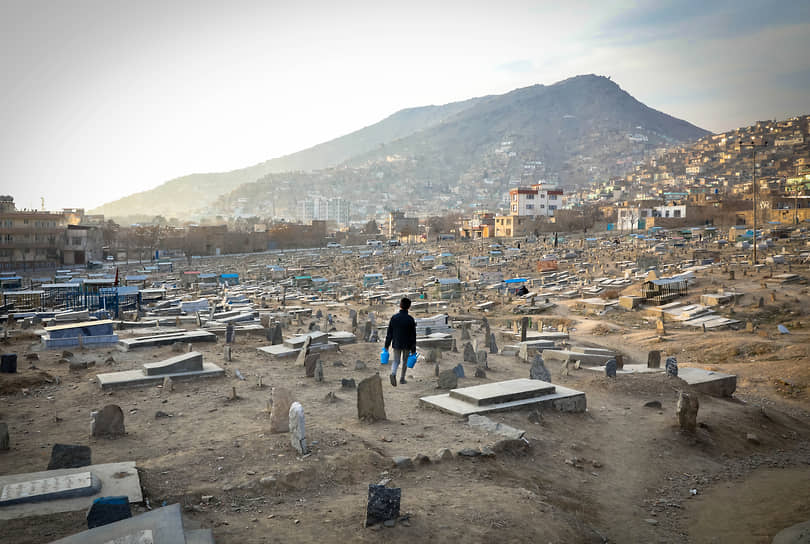 Кабул, Афганистан. Продавец воды идет через кладбище в поиске покупателей 