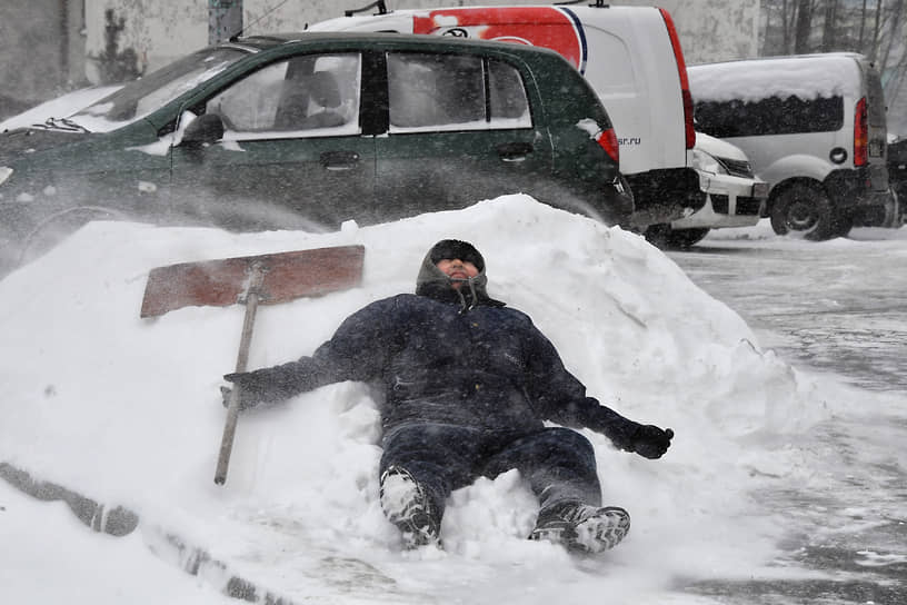 Москва. Сотрудник коммунальной службы отдыхает на снежном сугробе