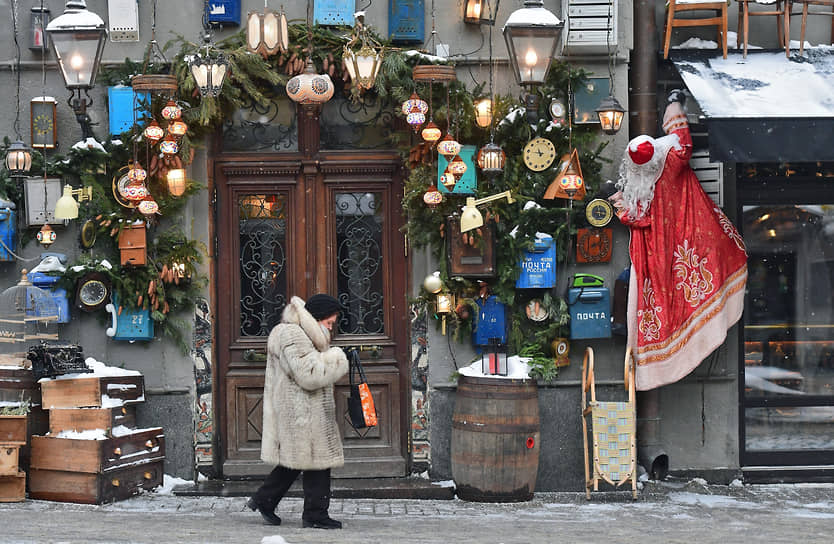 Москва, Россия. Женщина проходит мимо  еще по-новогоднему украшенного входа в паб «Black Swan Pub»