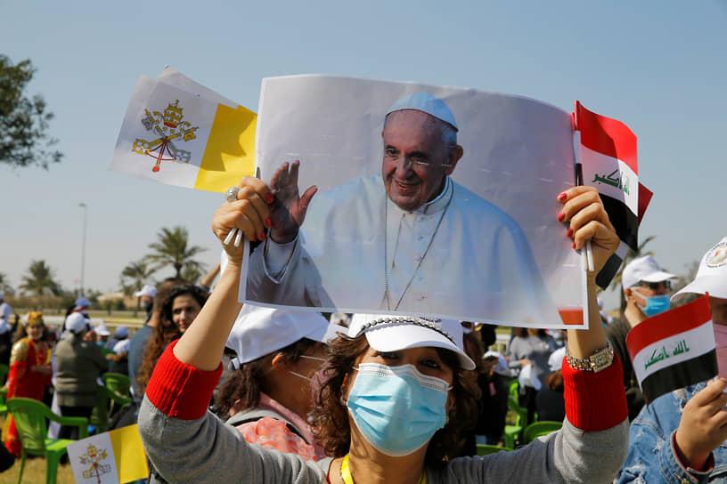 Женщина держит портрет папы Римского Франциска, встречая его на пути в аэропорт Багдада