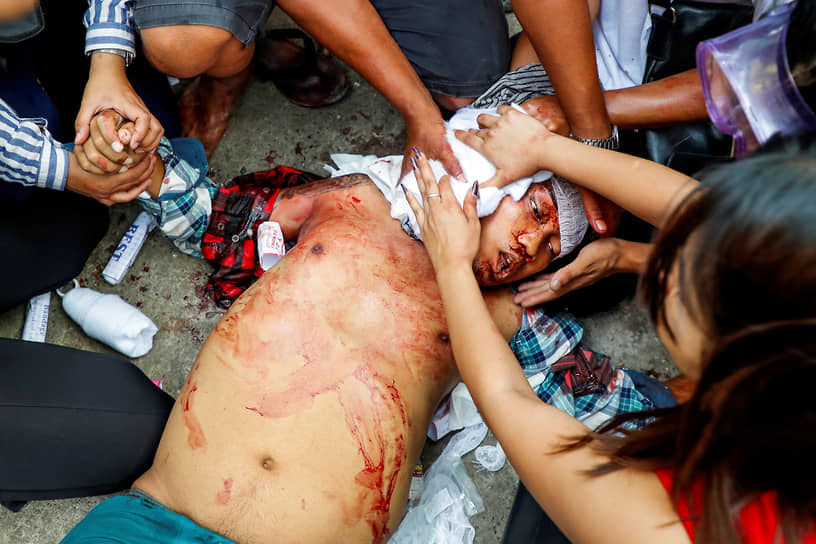 Раненому во время протестов пытаются оказать первую помощь