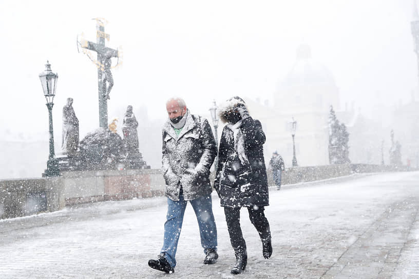 Прага, Чехия. Люди в снегу идут по Карлову мосту