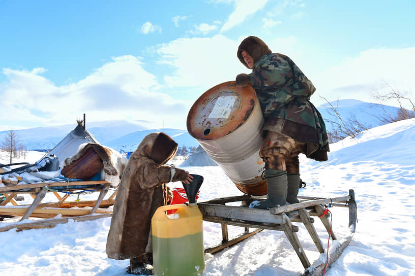 Мужчина переливает бензин из бака в канистру для заправки снегохода