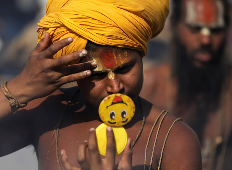 Хардвар, Индия. Индуистский аскет смотрит в зеркало перед утренней молитвой на берегу реки Ганг