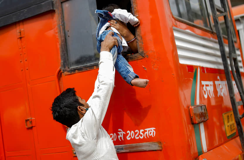 Газиабад, Индия. Мужчина передает своего сына через окно автобуса 