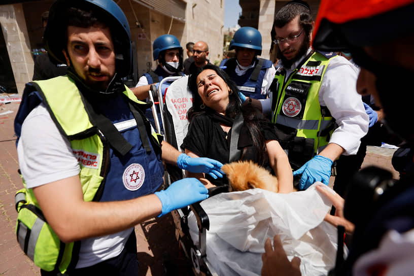 Медики эвакуируют женщину с места авиаудара «Хамаса» по израильскому Ашкелону