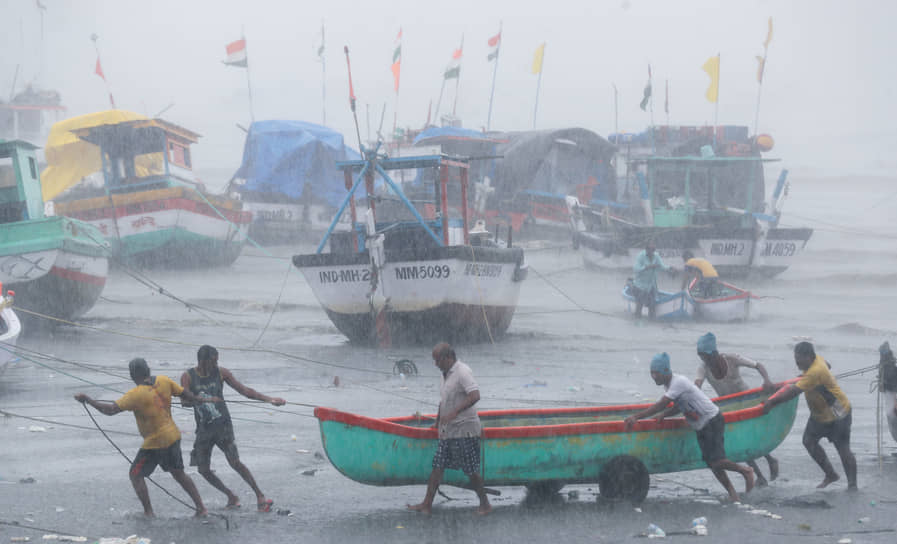 Мумбаи, Индия. Рыбаки перетаскивают лодку во время непогоды 