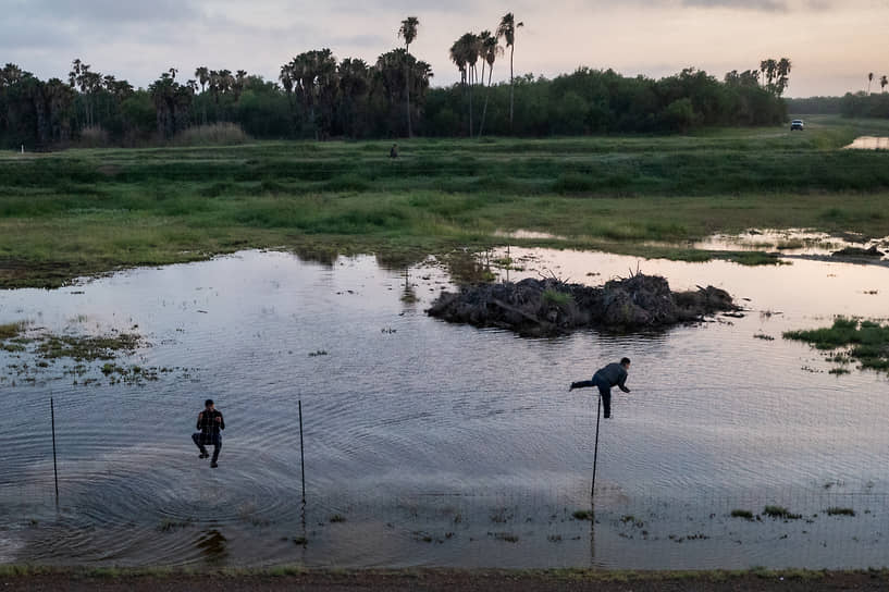 Ла Джойя, штат Техас, США. Мигранты перелезают через забор обратно в Мексику, уходя от американских пограничников