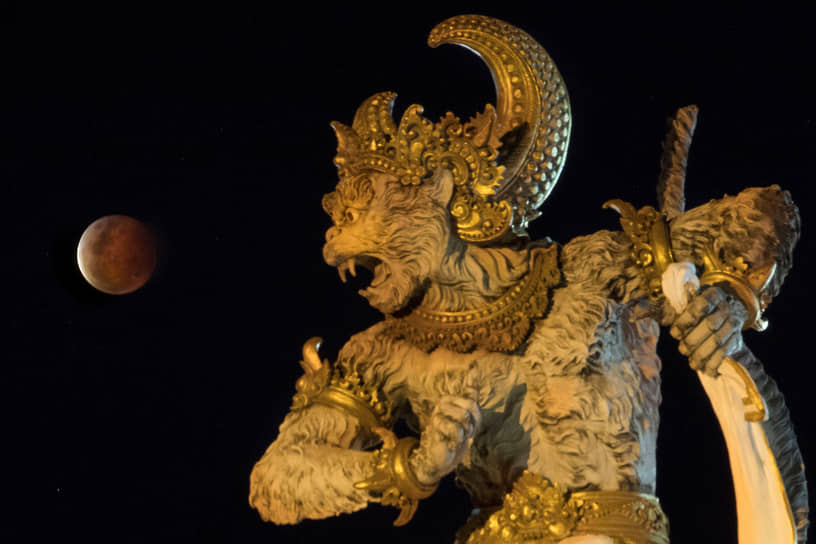 Денпасар, Индонезия. Фигура в парке на фоне полного лунного затмения 