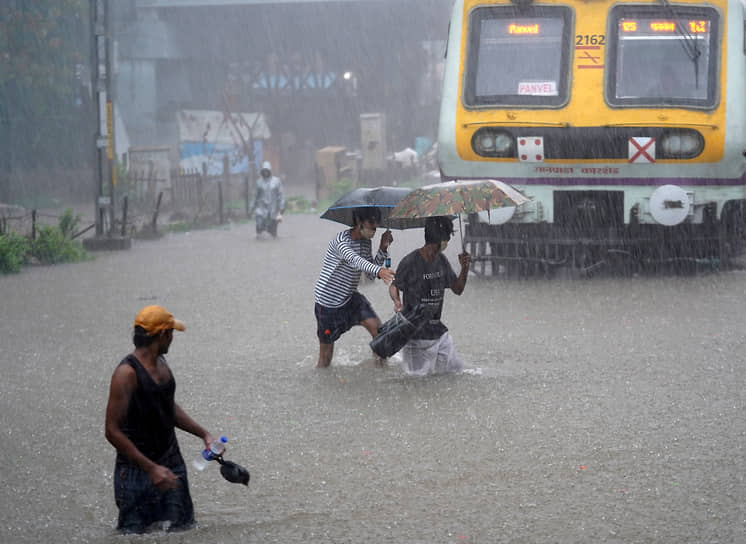 Мумбаи, Индия. Местные жители переходят железнодорожные пути, затопленные из-за проливных дождей