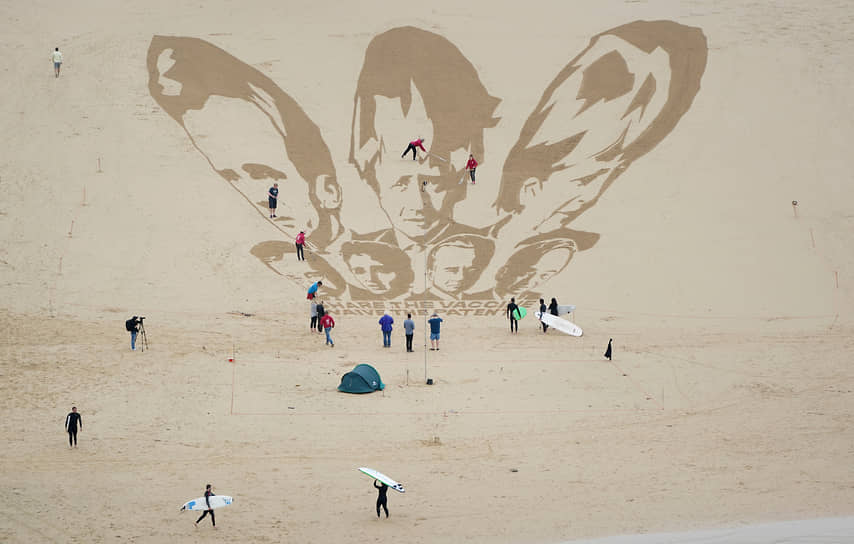 Корнуолл, Великобритания. Активисты наносят на песок изображение лидеров стран G7