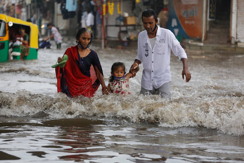 Ахмедабад, Индия. Семья идет по затопленной дороге 