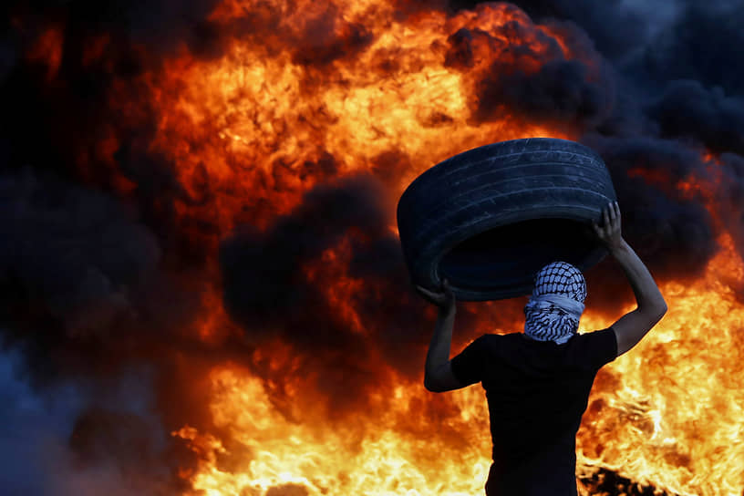 Бейта, Западный берег реки Иордан. Палестинский демонстрант несет шину 