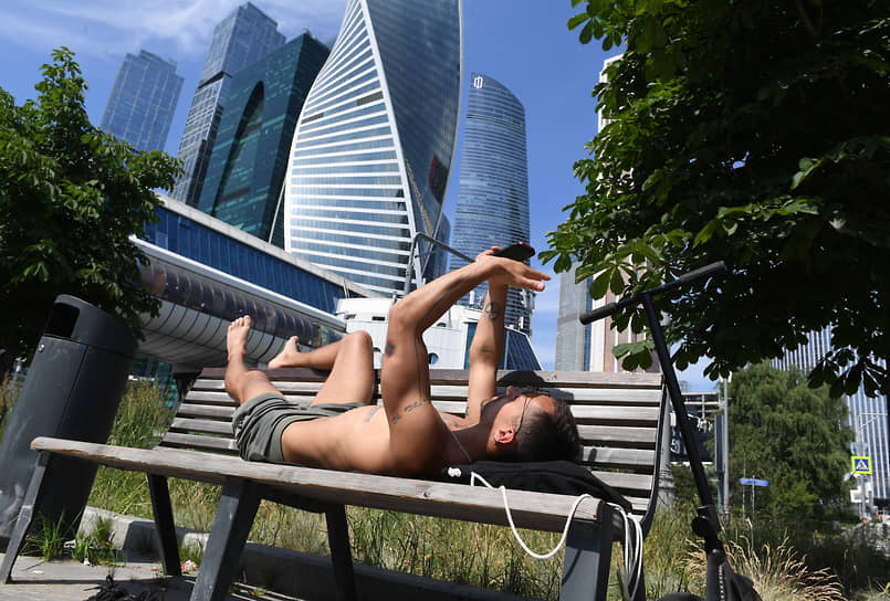 Мужчина отдыхает на лавочке на Пресненской набережной в Москве