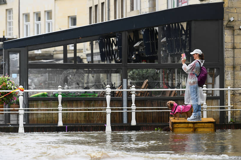 Женщина фотографирует затопленную улицу в Нидерландах