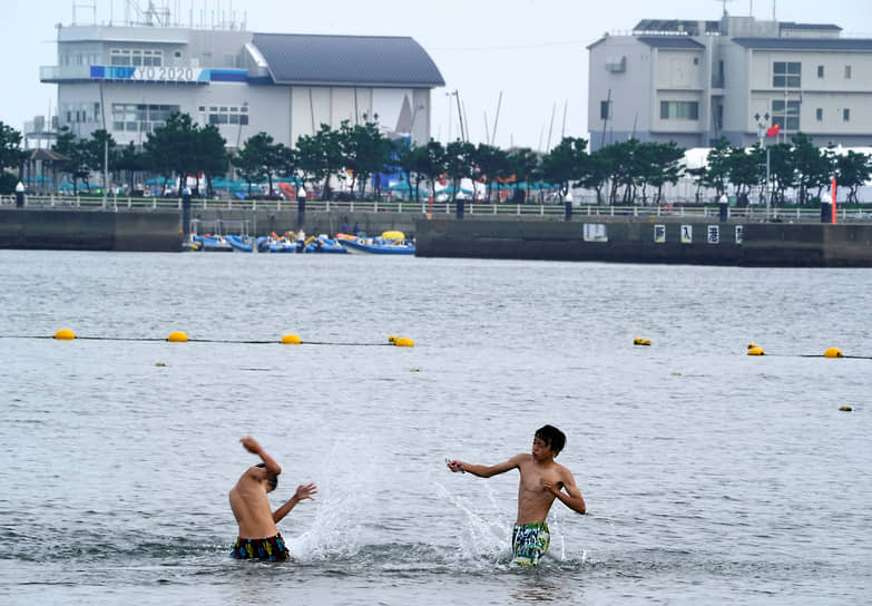 Молодые люди купаются неподалеку от места проведения соревнований по парусному спорту 
