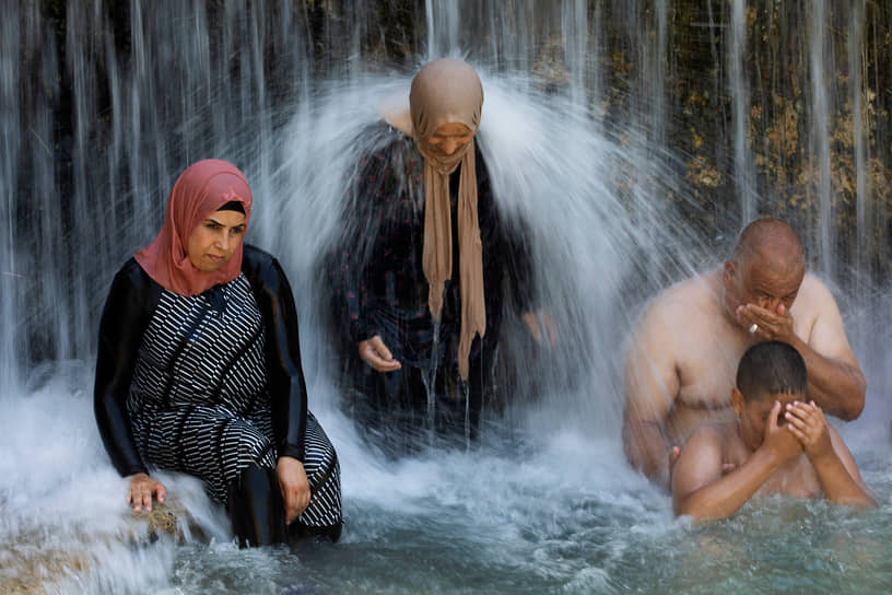 Бейт-Шеан, Израиль. Люди стоят под водопадом 
