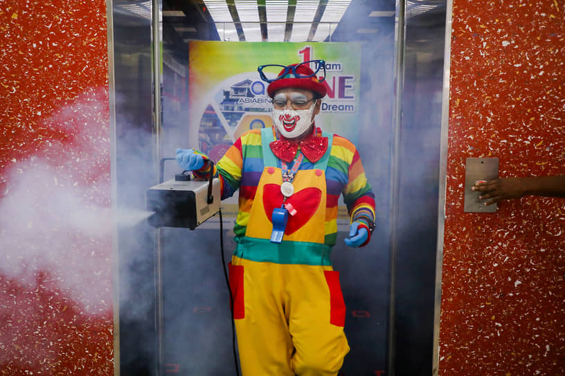 Тайпин, Малайзия. Мужчина в костюме клоуна дезинфицирует лифт в торговом центре