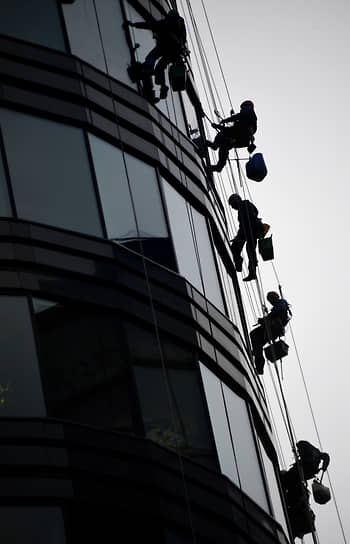 Москва, Россия. Промышленные альпинисты моют окна высотного здания 