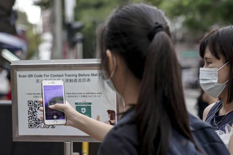 Посетители сканируют QR-код по системе SafeEntry, чтобы зайти в торговый центр в Сингапуре