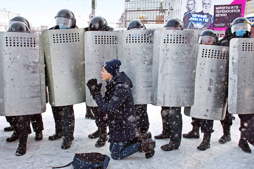 Участник митинга в поддержку Алексея Навального стоит на коленях перед оцеплением сотрудников полиции 