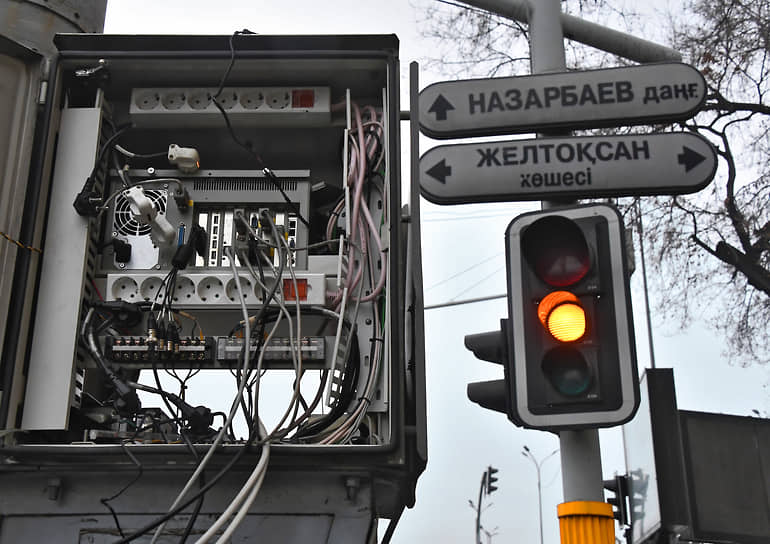 Столб с указателями и светофором рядом с распределительным электрощитом в Алматы