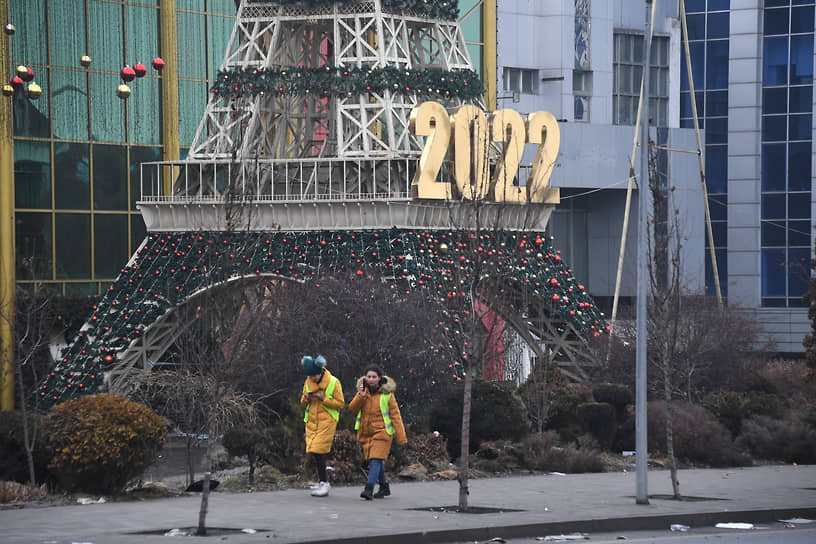 Женщины в светоотражающих жилетах на фоне новогодней елки в виде Эйфелевой башни