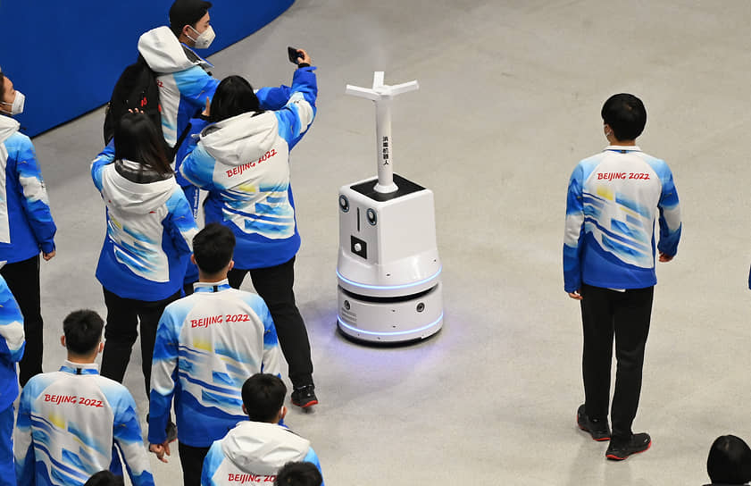 Сотрудники сервисной службы и робот-дезинфектор во время подготовки к матчу
