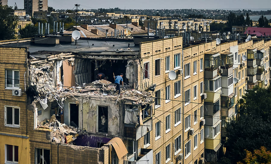 Мужчина разбирает завалы квартиры, разрушенной после обстрела в Никополе