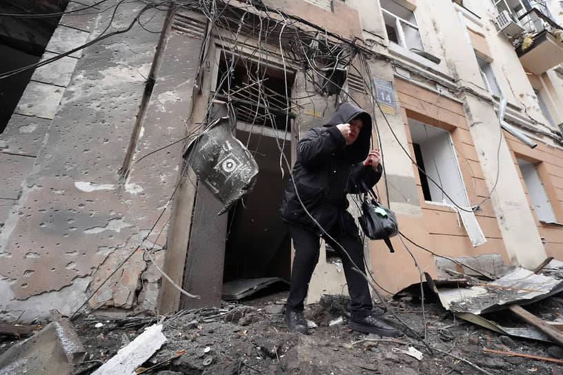 Жительница Харькова выходит из здания, разрушенного в результате обстрела