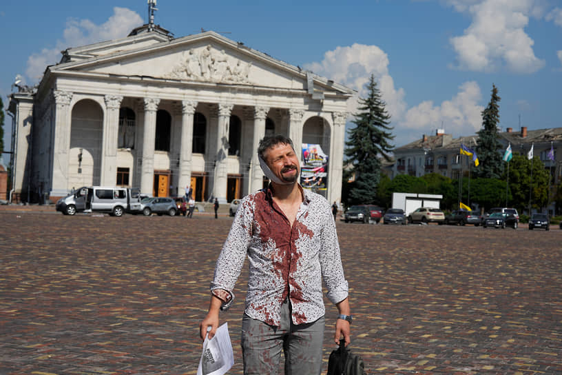 Раненый мужчина стоит на площади у Черниговского областного академического музыкально-драматического театра 