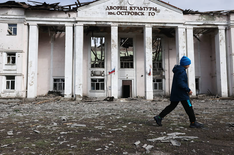 Мальчик проходит мимо разрушенного дворца культуры в поселке Золотое-5 ЛНР