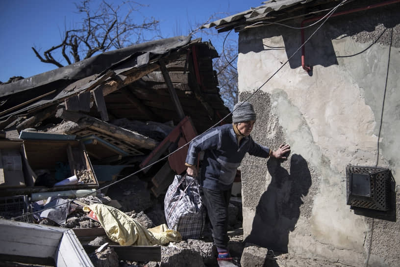 Женщина идет около дома, разрушенного в результате обстрела в городе Брянка ЛНР