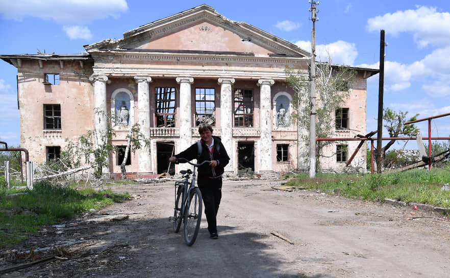 Женщина с велосипедом рядом с уничтоженным зданием в селе Тошковка в ЛНР