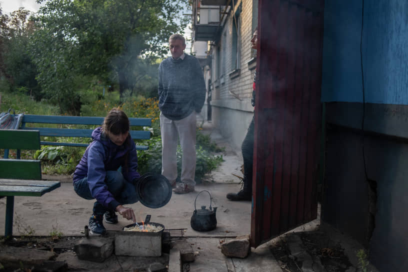 Местная жительница готовит еду у подъезда одного из домов в Лисичанске