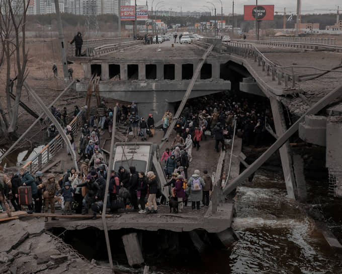 Люди переходят через разрушенный мост, пытаясь покинуть город Ирпень в Киевской области